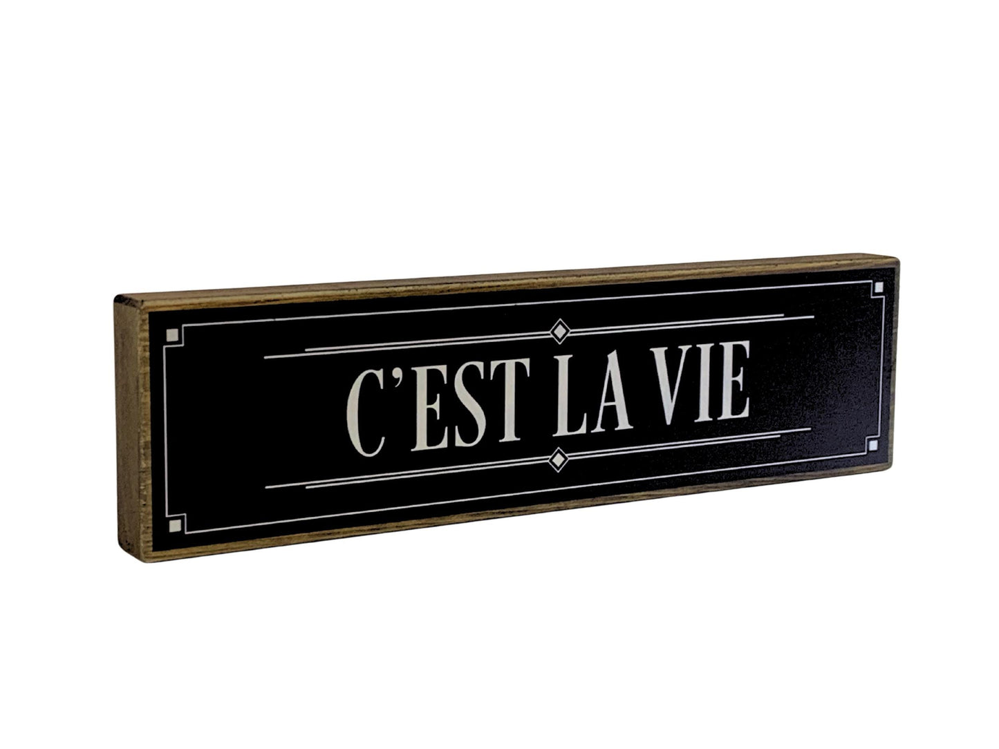Decorative sign with 'C'EST LA VIE' text on a black background