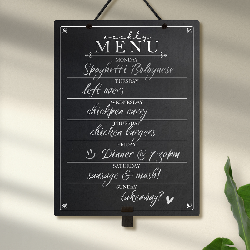 Large chalkboard hanging from black rope with weekly meal plan writen on it