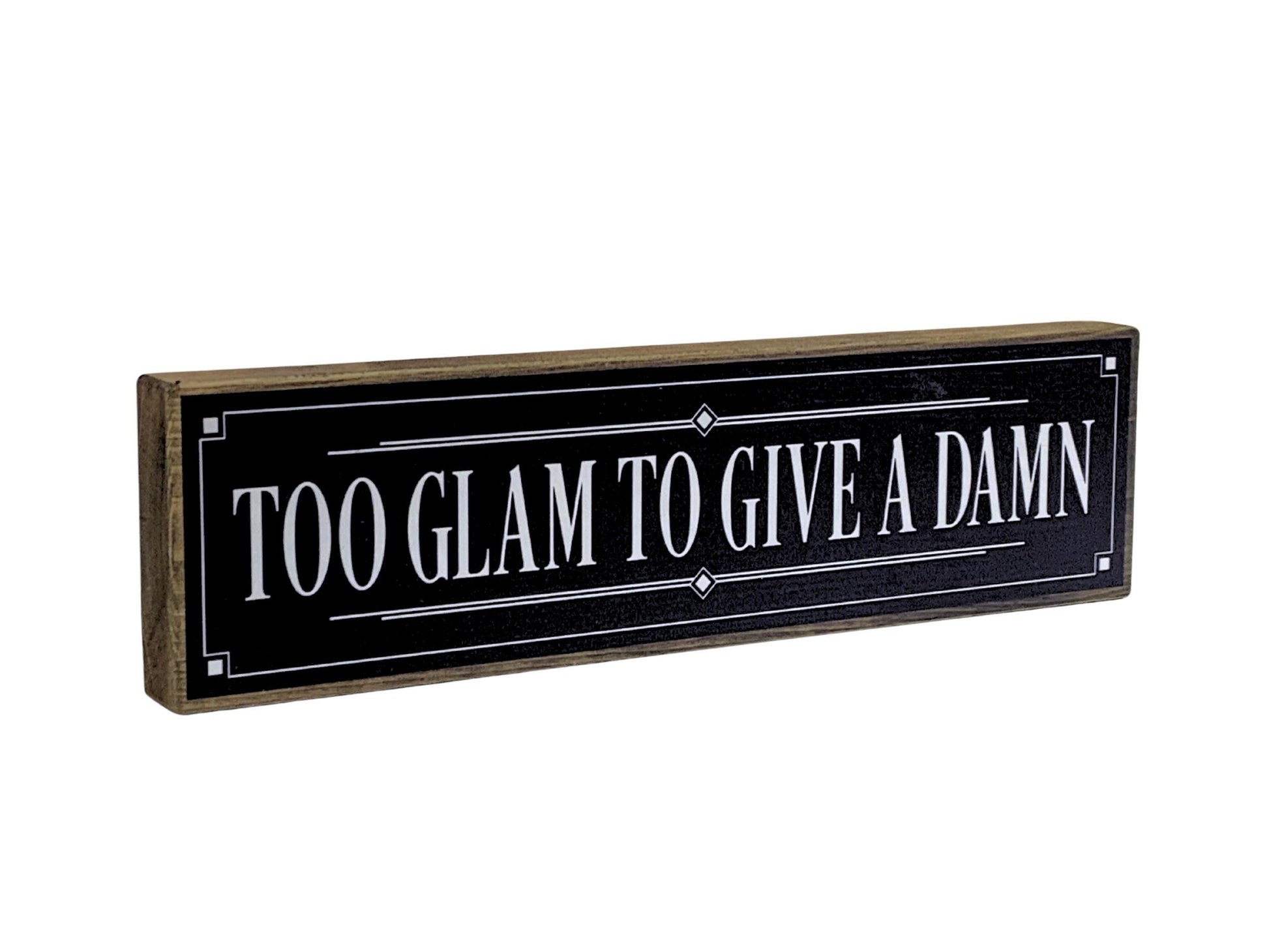 Decorative sign with text 'Too Glam To Give A Damn' on a black background