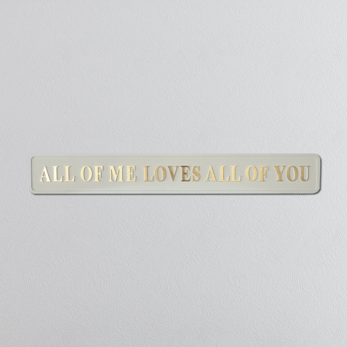Foil plaque with 'ALL OF ME LOVES ALL OF YOU' text on a light gray background