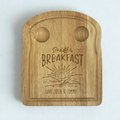 Wooden toast shaped serving board with 2 carved egg holders in the top, an engraved illustration of a sunset with 'Daddy's Breakfast' above it and a personalised message engraved at the bottom.