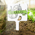 Garlic plant marker with garlic illustration and 'Garlic' text in a garden setting