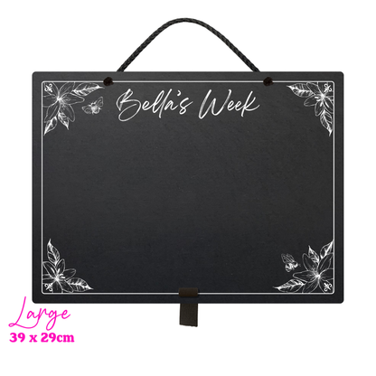 Large landscape chalkboard hanging with black rope and an adjustable pen holder at the bottom. Featuring sketchy floral illustrations framing a mostly empty space with 'Bella's Week' at the top in cursive font. In the bottom left hand corner it reads 'Large' and the measurements 39x29 cm