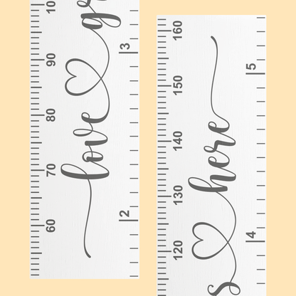 Close up of a white growth chart with the words 'love grows here' in cursive script printed up the center in grey