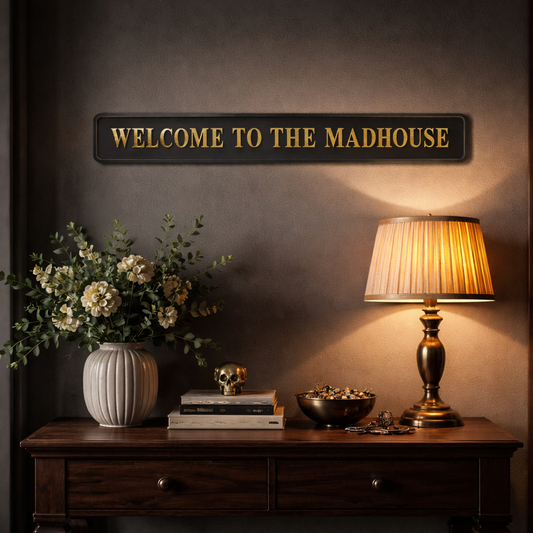 Black and gold foiled street sign with "welcome to the madhouse" wording in a stylish, cosy setting