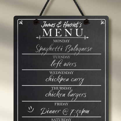 Close up of a medium chalkboard hanging from black rope, featuring the days of the week layed out down the center with sections for each day and the heading 'James & Harriet's Menu' at the top.