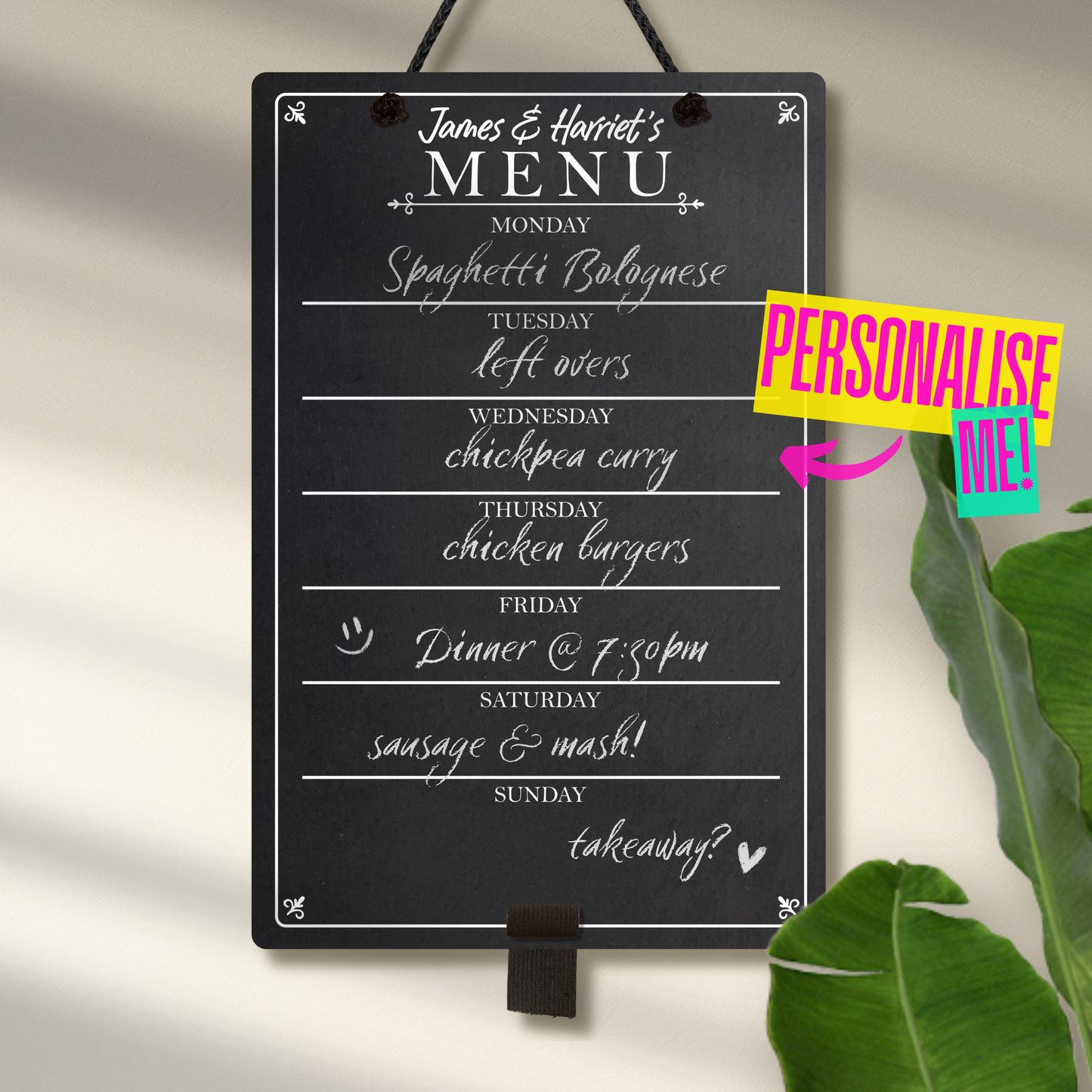 Medium chalkboard hanging from black rope with adjustable pen holder at the bottom. Featuring the days of the week layed out down the center with sections for each day and the heading 'James & Harriet's Menu' at the top. A colourful sign reads "Personalise me!" whilst pointing towards the product.
