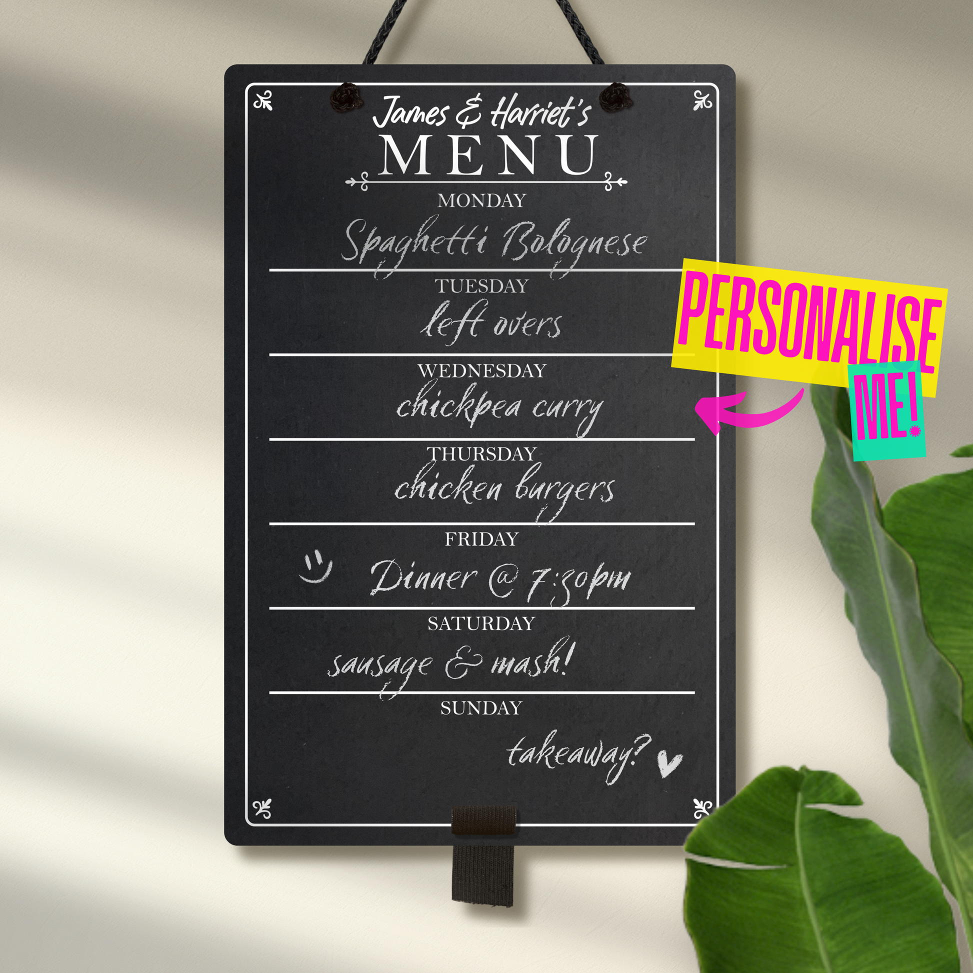 Medium chalkboard hanging from black rope with adjustable pen holder at the bottom. Featuring the days of the week layed out down the center with sections for each day and the heading 'James & Harriet's Menu' at the top. A colourful sign reads "Personalise me!" whilst pointing towards the product.
