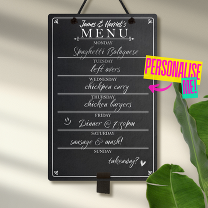 Medium chalkboard hanging from black rope with adjustable pen holder at the bottom. Featuring the days of the week layed out down the center with sections for each day and the heading 'James & Harriet's Menu' at the top. A colourful sign reads "Personalise me!" whilst pointing towards the product.