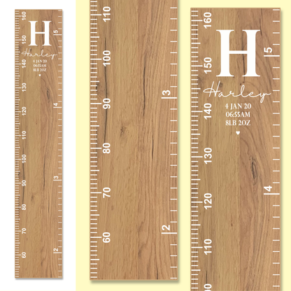 Wooden growth chart with white measurements and personalised name, initial and birth information, including date, time and weight
