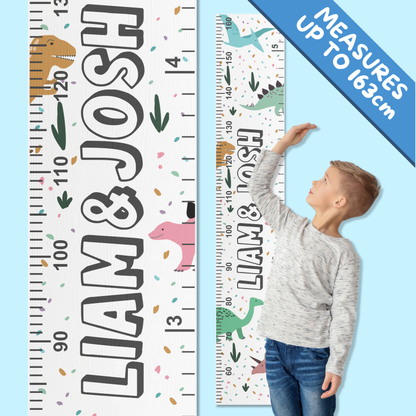 Growth ruler with colourful cartoon dinosaurs on it, personalised with 2 boys names. Shown with a boy using it to measure his height.