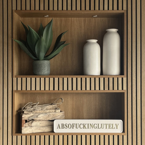 Cream 'absofuckinglutely' street sign with gold foiled text in a calming setting