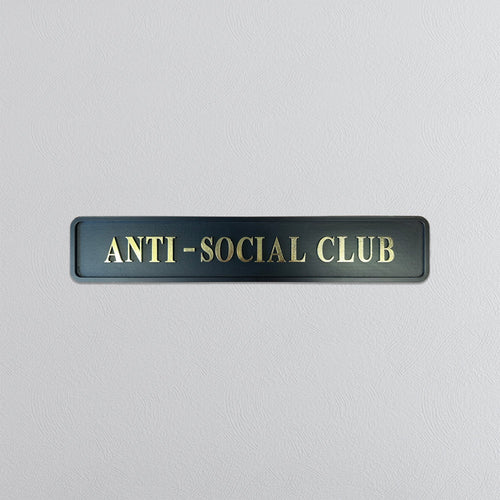 Black street sign with 'ANTI-SOCIAL CLUB' gold text on a light gray background