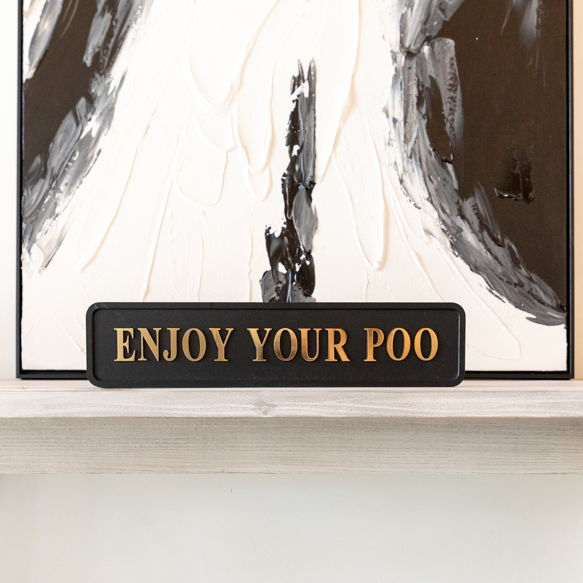 Black and gold foiled street sign with 'Enjoy Your Poo' wording