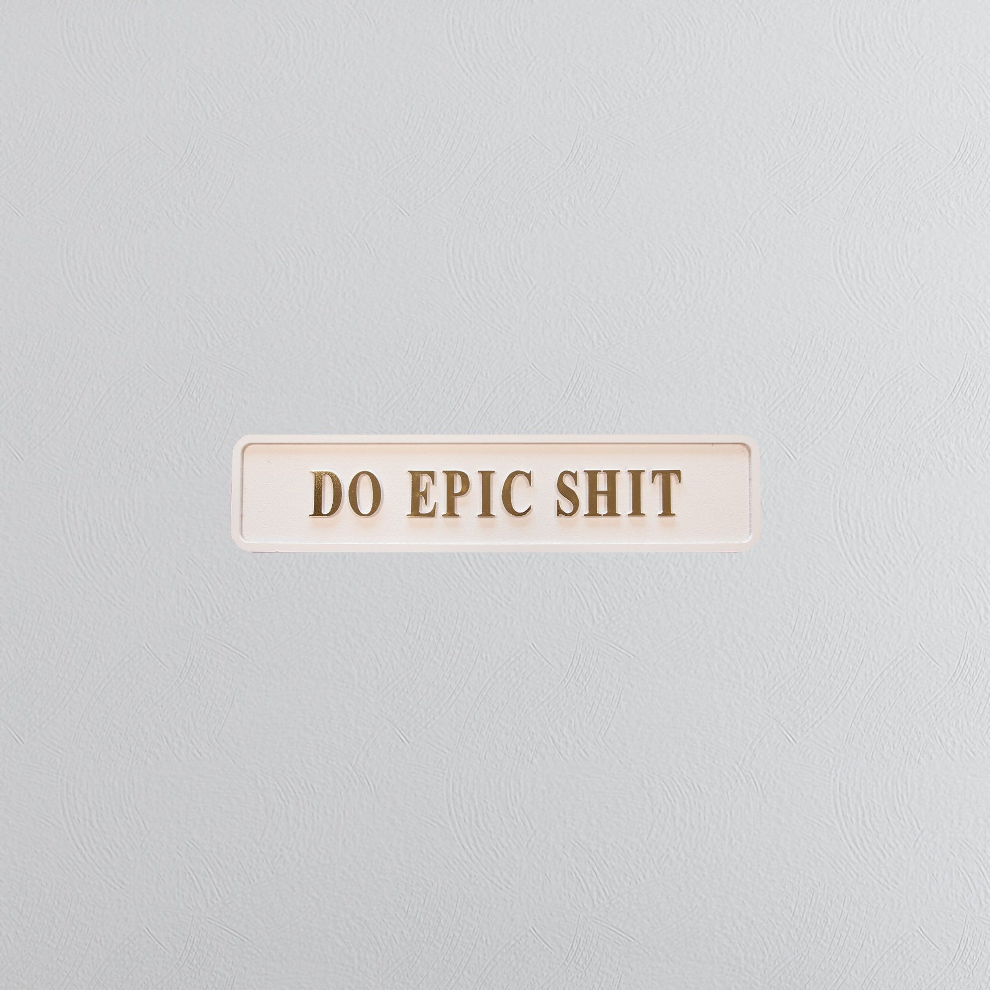 Cream and gold foiled street sign with "do epic shit" lettering
