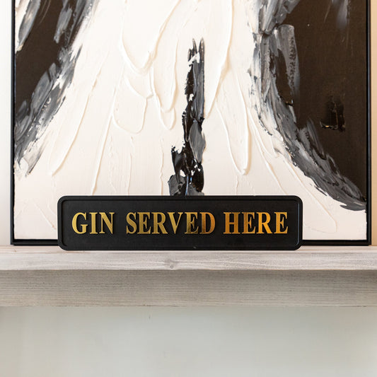 Black and gold foiled street sign with 'Gin served here' wording