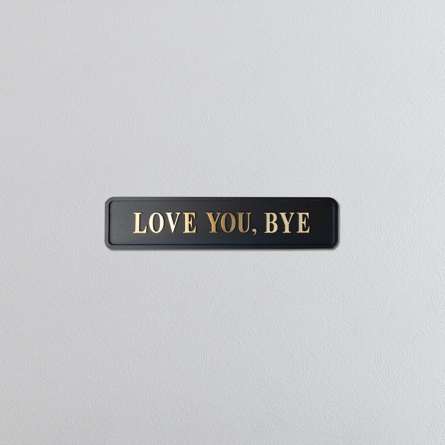 Black and gold foiled street sign with "love you, bye" lettering 