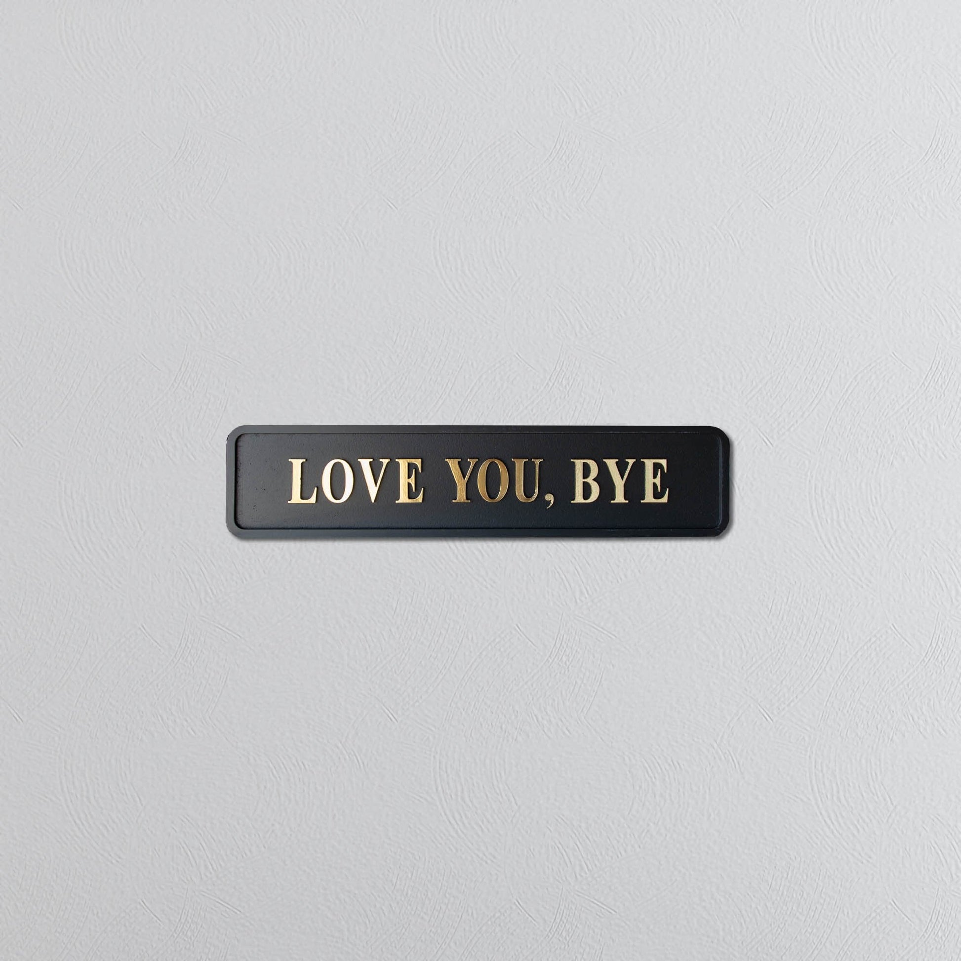 Black and gold foiled street sign with "love you, bye" lettering 