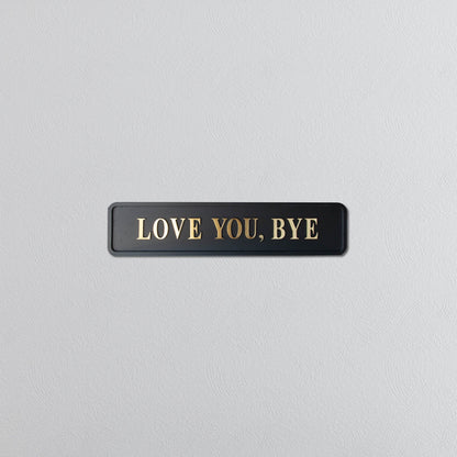 Black and gold foiled street sign with "love you, bye" lettering 