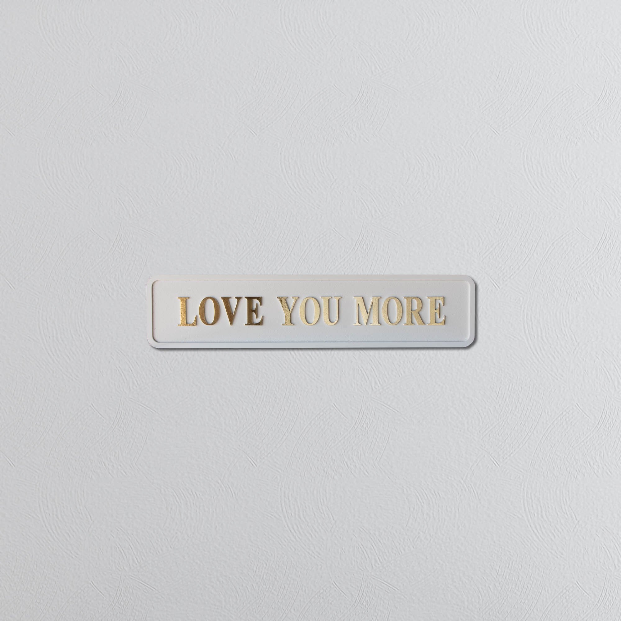 Cream and gold foil plaque with 'LOVE YOU MORE' text on a light gray background