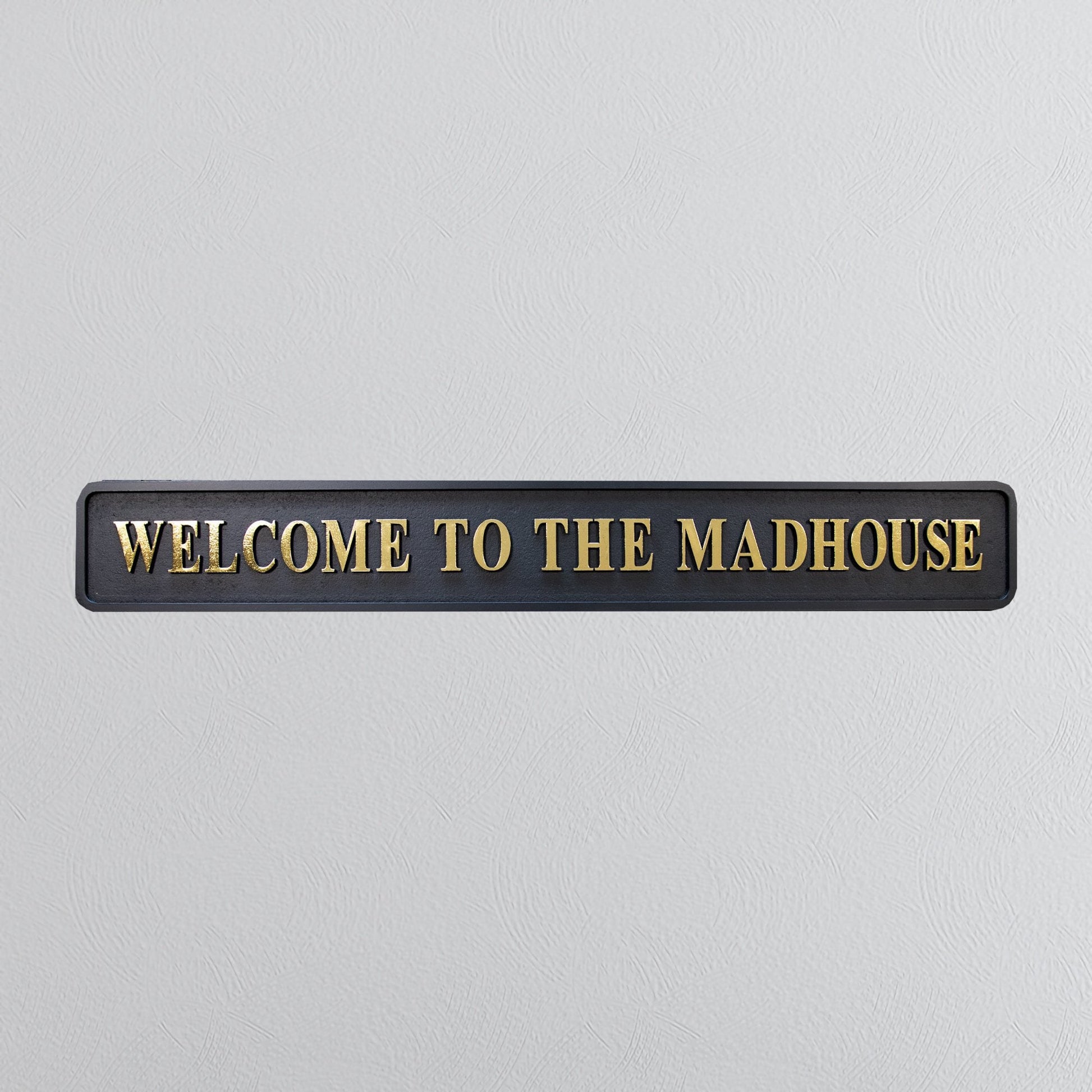 Black and gold foiled street sign with "welcome to the madhouse" wording