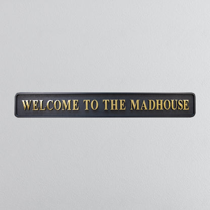 Black and gold foiled street sign with "welcome to the madhouse" wording