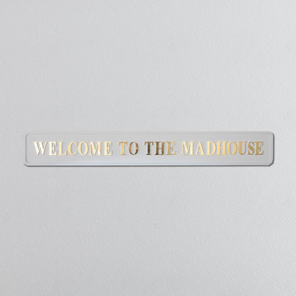 Cream and gold foiled street sign with "welcome to the madhouse" wording 