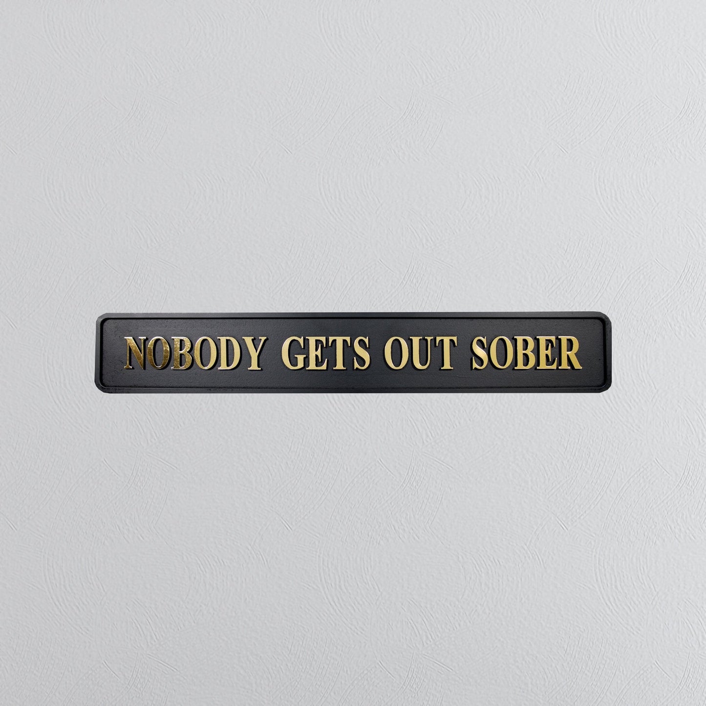 Black and gold foiled street sign with "nobody gets out sober" lettering