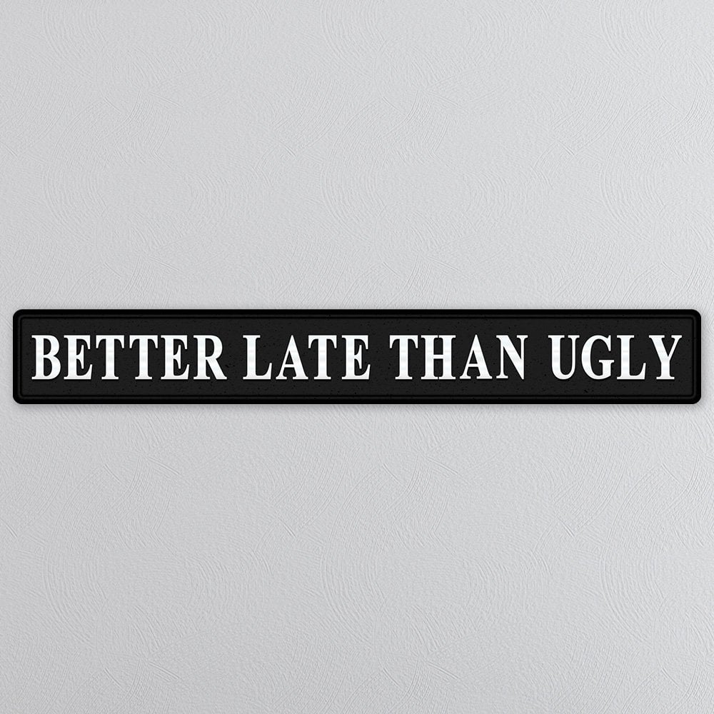 Black sign with silver text 'BETTER LATE THAN UGLY' on a light gray background