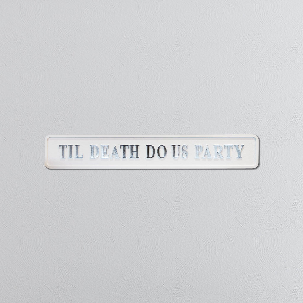 Decorative sign with 'TIL DEATH DO US PARTY' in silver text on a light gray background