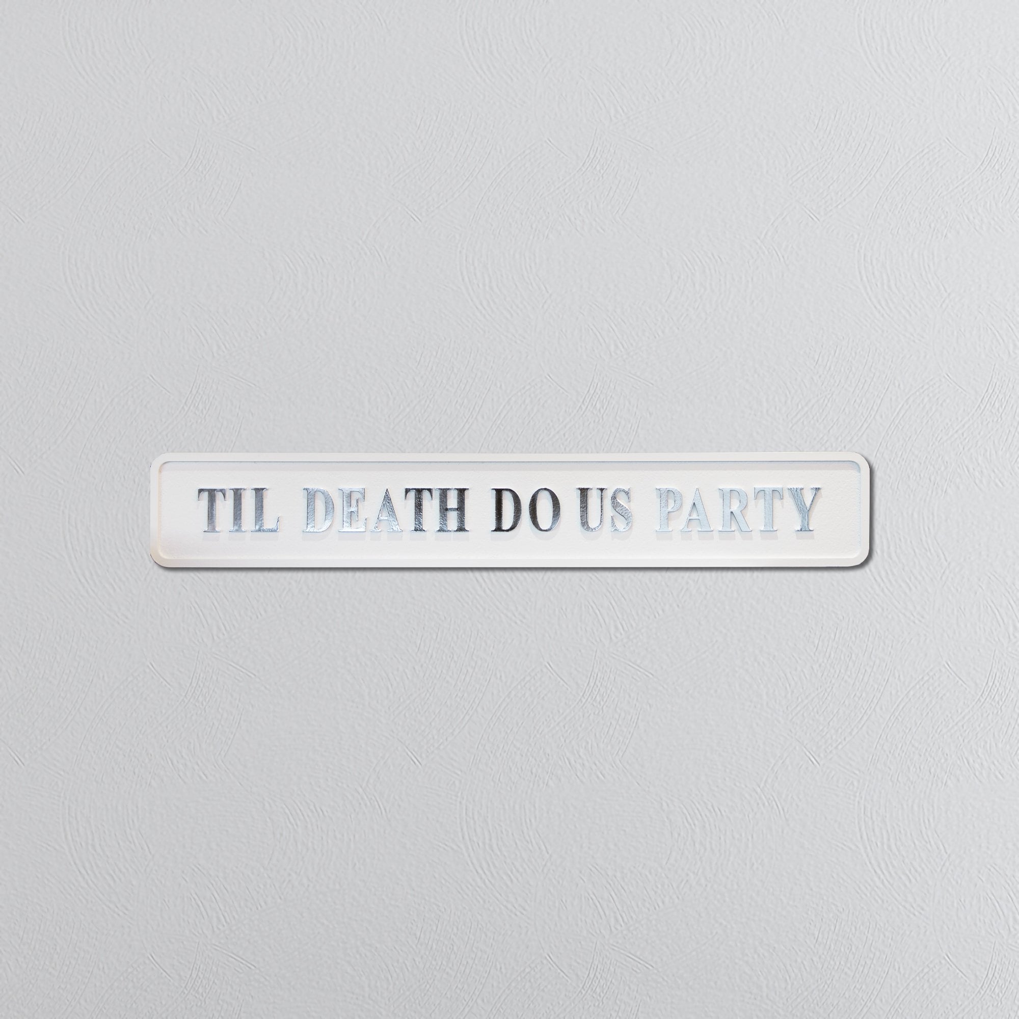 Decorative sign with 'TIL DEATH DO US PARTY' in silver text on a light gray background