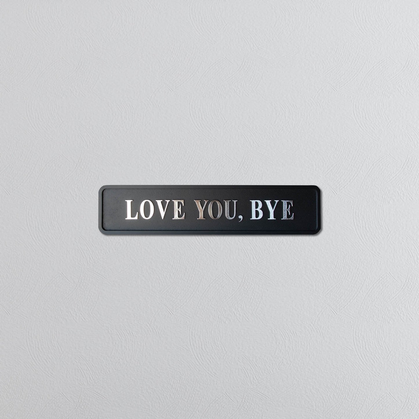 Black and silver foiled street sign with "love you, bye" lettering