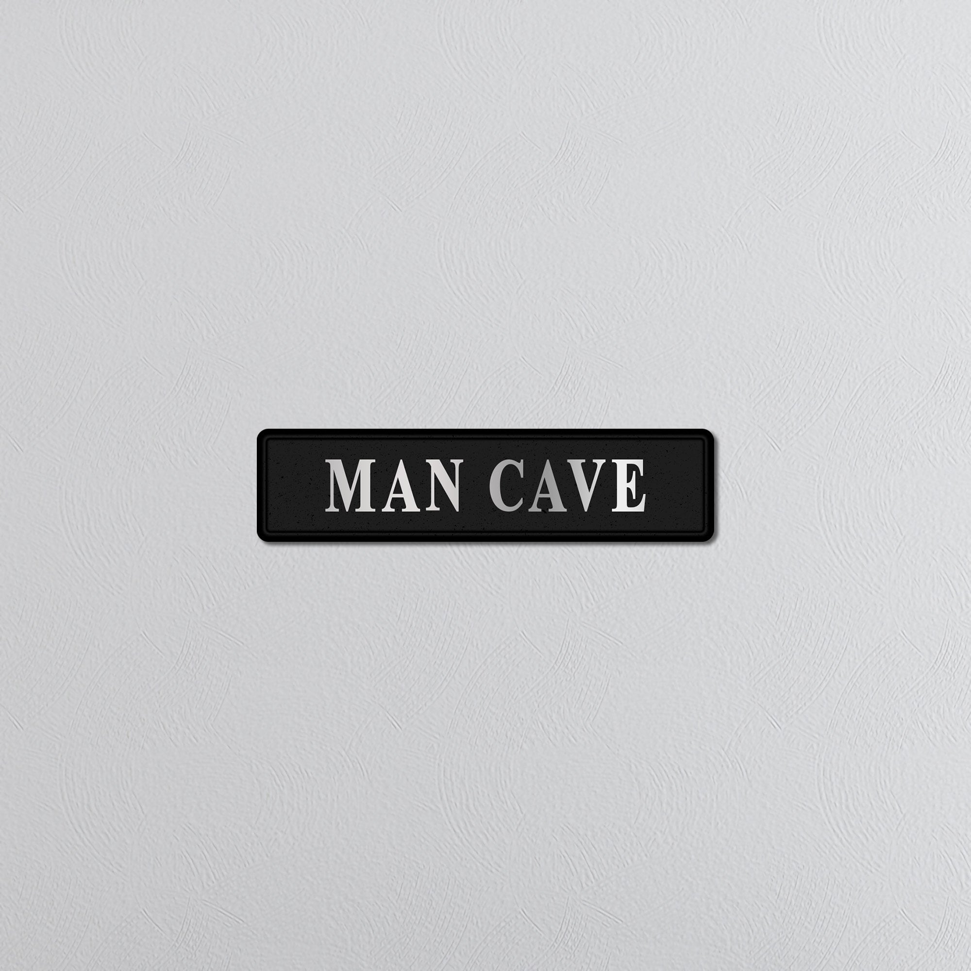 Black rectangular sign with 'MAN CAVE' text on a light gray background