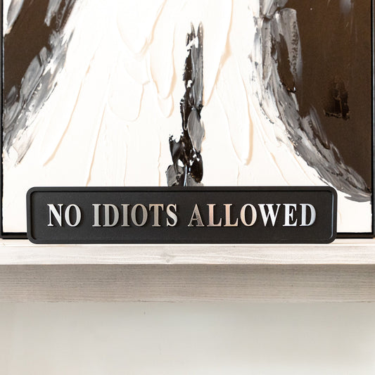 Black and silver foiled street sign with 'No idiots allowed' wording