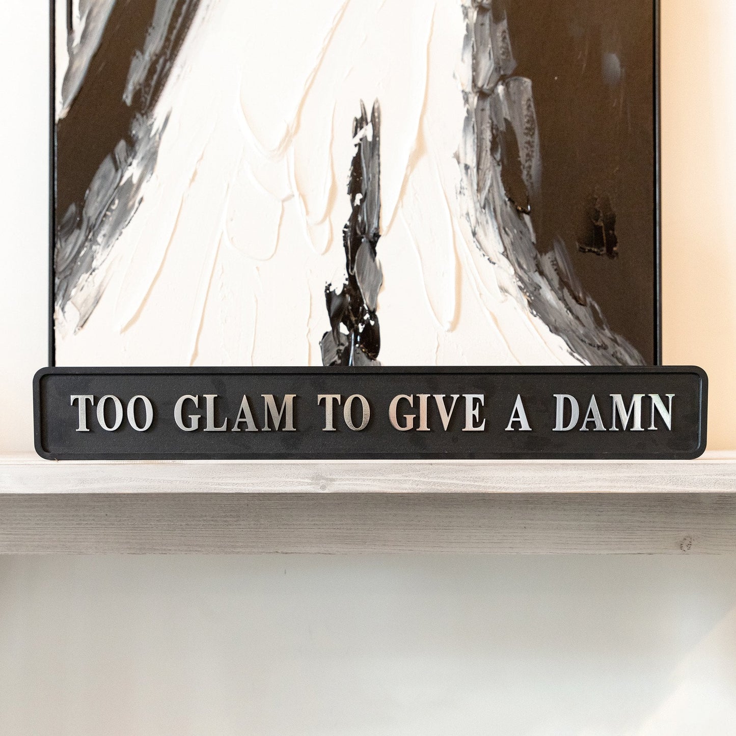 Black and silver foiled street sign with 'Too glam to give a damn' wording