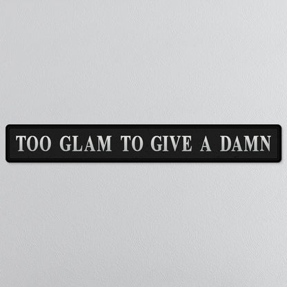 Black and silver foiled street sign with 'Too glam to give a damn' wording
