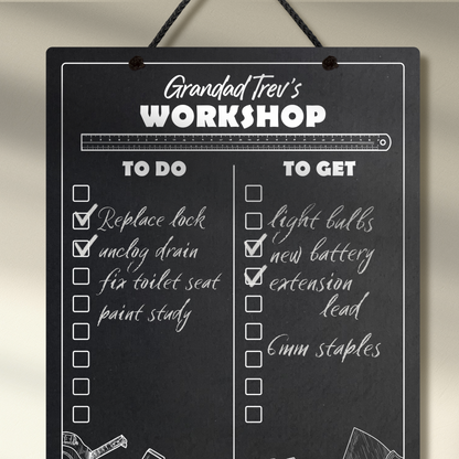 Close up of a chalkboard hanging from a black rope, featuring "to do" and "to get" collumn headers and check boxes printed with "Grandad Trev's Workshop" printed at the top. Example chalk notes listing items to be done and bought added.